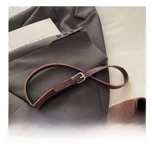 Close-up of adjustable metal buckle and lychee grain leather strap on a brown bag