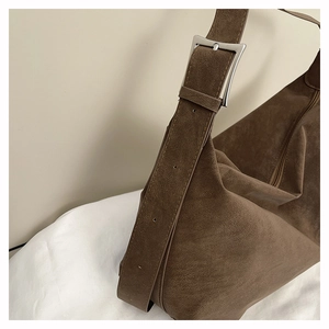 Detailed close-up of dark brown suede tote bag featuring a wide strap and silver metal buckle