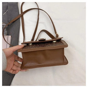 Vue détaillée du bas d'un sac à main marron avec logo imprimé et fermoir doré chic