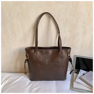Detail view of large vintage brown tote bag featuring side drawstrings and gold metal buckles