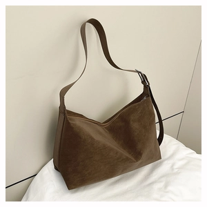 Detail of dark brown matte leather tote bag featuring a silver buckle and adjustable strap