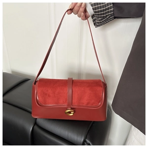 Detail of red leather bag with suede patchwork and a prominent gold G-buckle closure