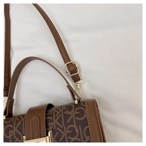 Gros plan d'un sac à monogramme marron foncé avec d'élégantes ferrures en métal doré