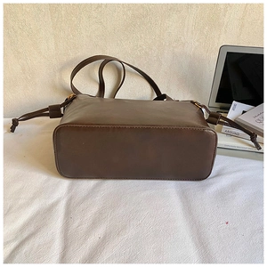 Detail of soft vintage brown leather tote bag with drawstring side on white fabric