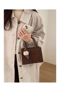 Detail of leopard print crossbody bag with cute plush ice cream charm and top handle