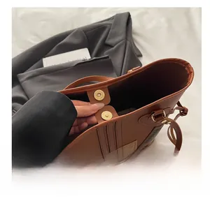 Close-up of magnetic hardware buckle and fine leather texture on brown tote bag
