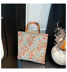 Detail of floral tapestry tote bag featuring natural bamboo handles and retro flower patterns