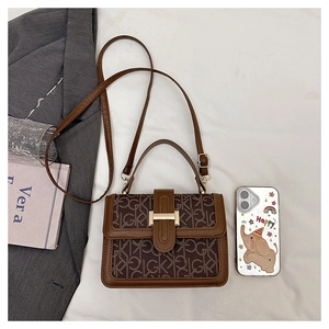 Gros plan du sac à main monogramme marron avec boucle dorée sur tissu blanc