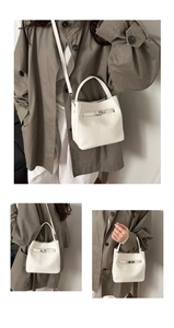 Detail of white lychee leather bucket bag with metal twist lock and shoulder strap