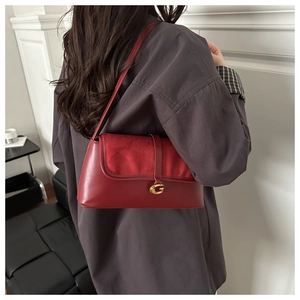 Detail view of a red shoulder bag featuring textured leather and a gold G-buckle closure