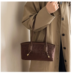 Brown leopard print tote bag with brown straps and metallic knot details on beige trench coat
