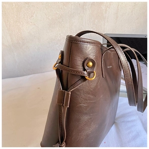 Close-up of brown wax leather tote with drawstring side and vintage gold hardware