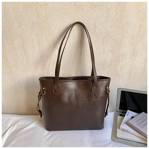 Detail of dark brown glossy tote bag with dual handles and side drawstring hardware