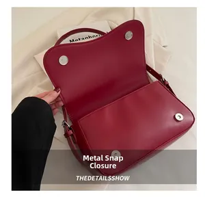 Dettaglio della borsa a tracolla rossa con chiusure magnetiche in argento e cuciture pulite