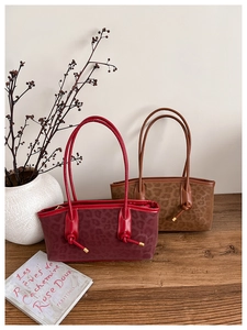 Detail view of leopard print suede totes in burgundy and brown with long handles