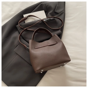 Detailed view of brown litchi grain leather bag featuring silver base protective studs