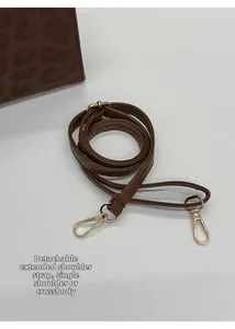 Detail of adjustable deep brown detachable shoulder strap with golden metal spring hooks