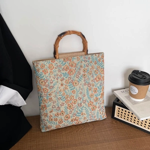 Floral jacquard tote bag with natural bamboo handles in a modern minimalist interior setting