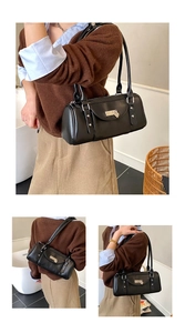 Détail du sac baguette noir avec breloque cœur et finitions métalliques argent