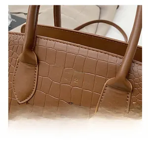 Close-up of brown crocodile texture leather and golden New York lettering on the handbag