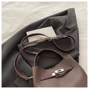 Detailed view of brown lychee grain leather bucket bag with vintage silver turn-lock closure