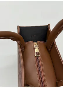 Detail of premium gold-toned zipper and brown leather handle on a stylish leopard tote bag