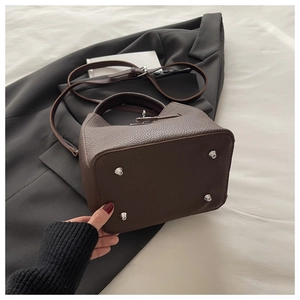 Detail view of brown pebbled leather bucket bag base with protective silver metal studs