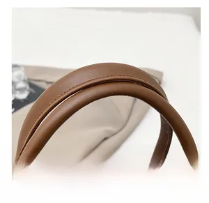 Close-up of brown crocodile texture handbag handle with reinforced stitching