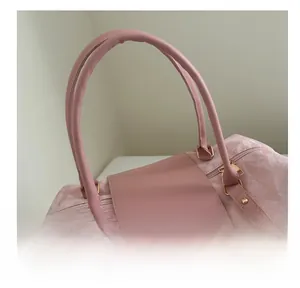 Close-up of comfortable double handles and gold metal hardware on pink travel bag