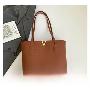 Detail view of brown pebbled tote bag with golden V logo on dark grey blazer background