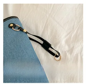 Detailed close-up of exquisite gold metal hardware and black leather strap on denim tote bag