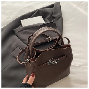 Detailed macro view of dark brown lychee grain leather bag with silver metal turn-lock
