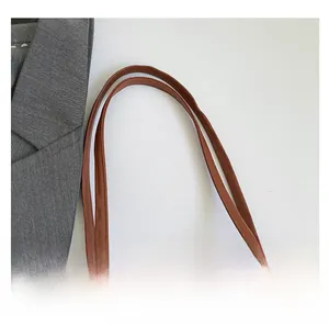 Detail of comfortable brown leather tote handles with high-quality stitching and texture