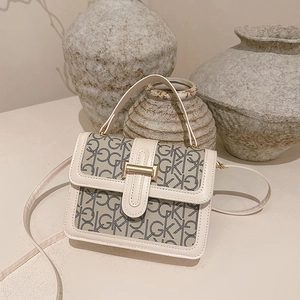 Sac à main carré à monogramme chic avec boucle dorée et finitions cuir sur fond beige
