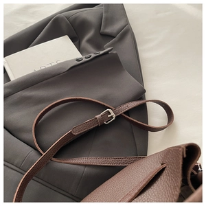 Detail of adjustable brown leather shoulder strap with silver buckle on a crossbody bag