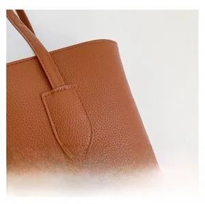 Detail of brown litchi pattern leather bag with reinforced stitching on the shoulder strap