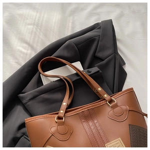 Detail of brown PU leather tote bag with heart-shaped strap fixings and gold rivets