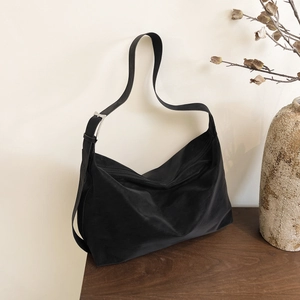 Borsa hobo nera capiente con tracolla regolabile su un tavolo di legno scuro