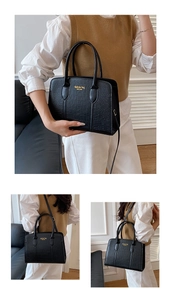 Detail of black crocodile pattern Boston bag with gold New York logo and versatile straps