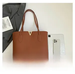 Detail view of large brown leather tote bag with gold V-buckle and iPad size comparison