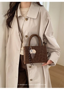 Detail of leopard print handbag with brown leather strap and plush ice cream charm