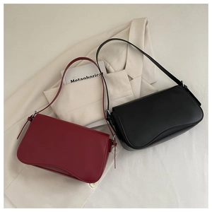 Dettaglio delle borse a spalla minimaliste in pelle bordeaux e nera con patta ondulata
