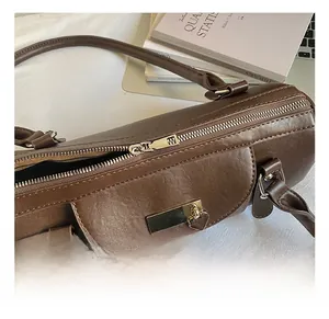 Détail du sac bowling marron foncé avec fermeture éclair dorée et pendentif en cœur