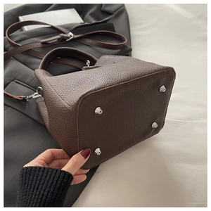 Detailed bottom view of brown lychee grain leather bucket bag with silver metal studs