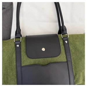 Detail of green faux suede tote with black leather trim and silver metal hardware