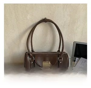 Détail d'un sac polochon marron avec pendentif cœur et rivets argentés pour le travail