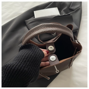 Detail of dark brown lychee grain leather handbag with silver magnetic snap closure