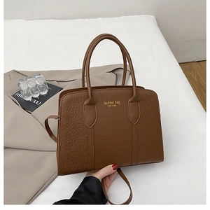 Dettaglio della borsa marrone con trama a coccodrillo e scritta dorata New York