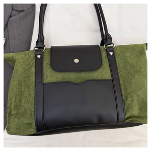 Detail of olive green suede and black leather patchwork tote with front pocket and handles
