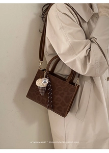 Detail of leopard print tote bag with plush ice cream charm and adjustable strap